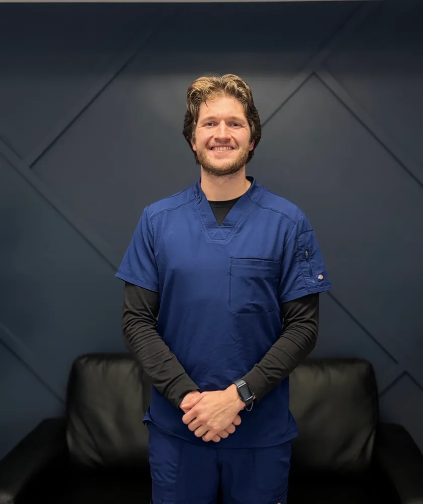 Dr. Caleb Fuller, DDS, smiling in blue scrubs in the dental office