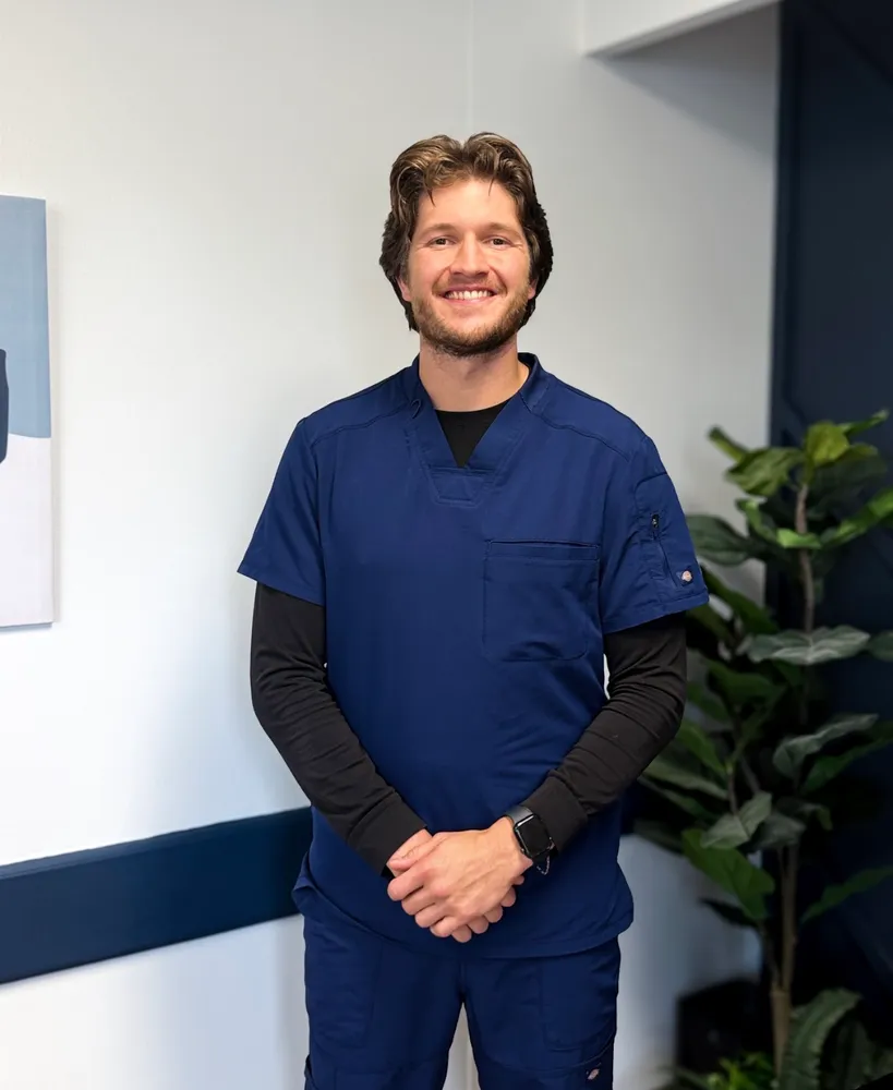 Dr. Caleb Fuller, smiling in navy scrubs in the dental office
