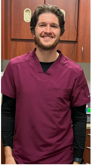 Dr. Caleb Fuller, smiling in maroon scrubs